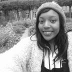 black and white photo of a woman wearing a beanie hat, in a garden